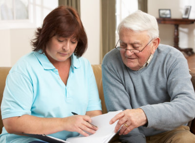 senior man in discussion with health visitor at home